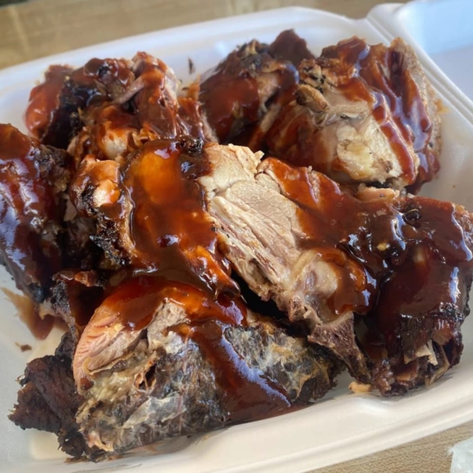 Close-up of OSU Jerk Grill's Caribbean jerk chicken pieces, generously coated in a rich, dark sauce.