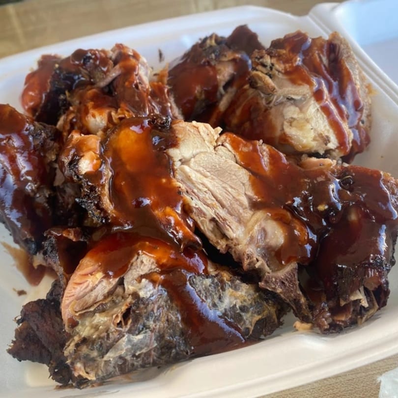 Close-up of OSU Jerk Grill's Caribbean jerk chicken pieces, generously coated in a rich, dark sauce.