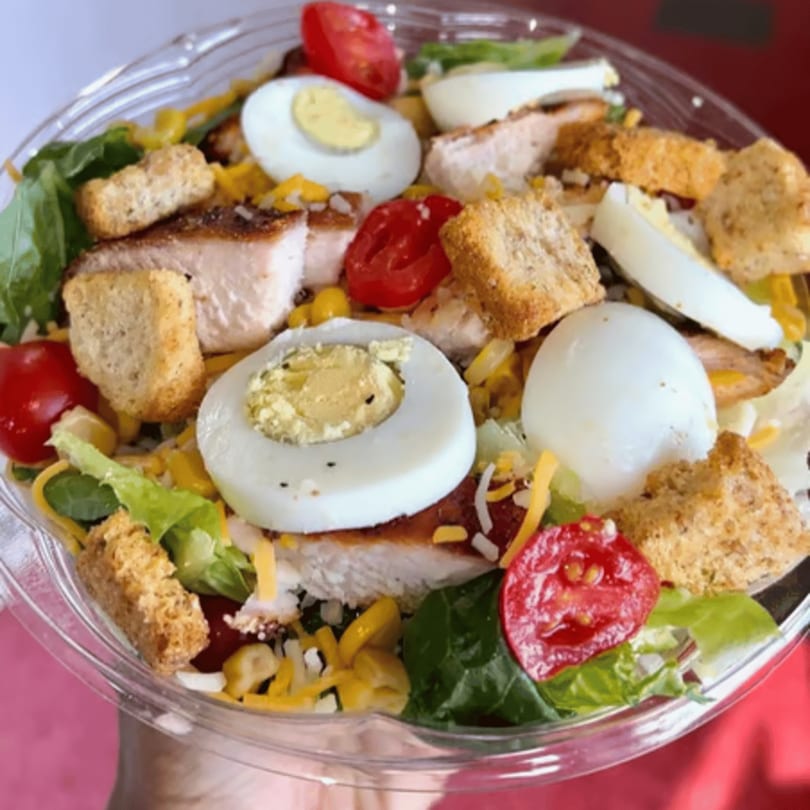 OSU Jerk Grill's vibrant salad with jerk chicken, hard-boiled eggs, tomatoes, croutons, and cheese.